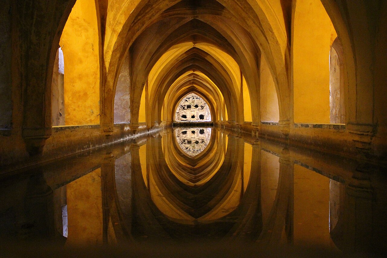 Patio abovedado de piedra con estanque del Real Alcázar de Sevilla